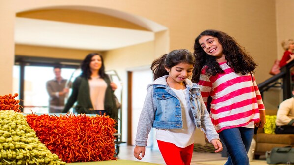 A group of people walking in a hallway with a display of colorful textiles. - Holiday Inn Chicago O'Hare Area by IHG (Chicago)