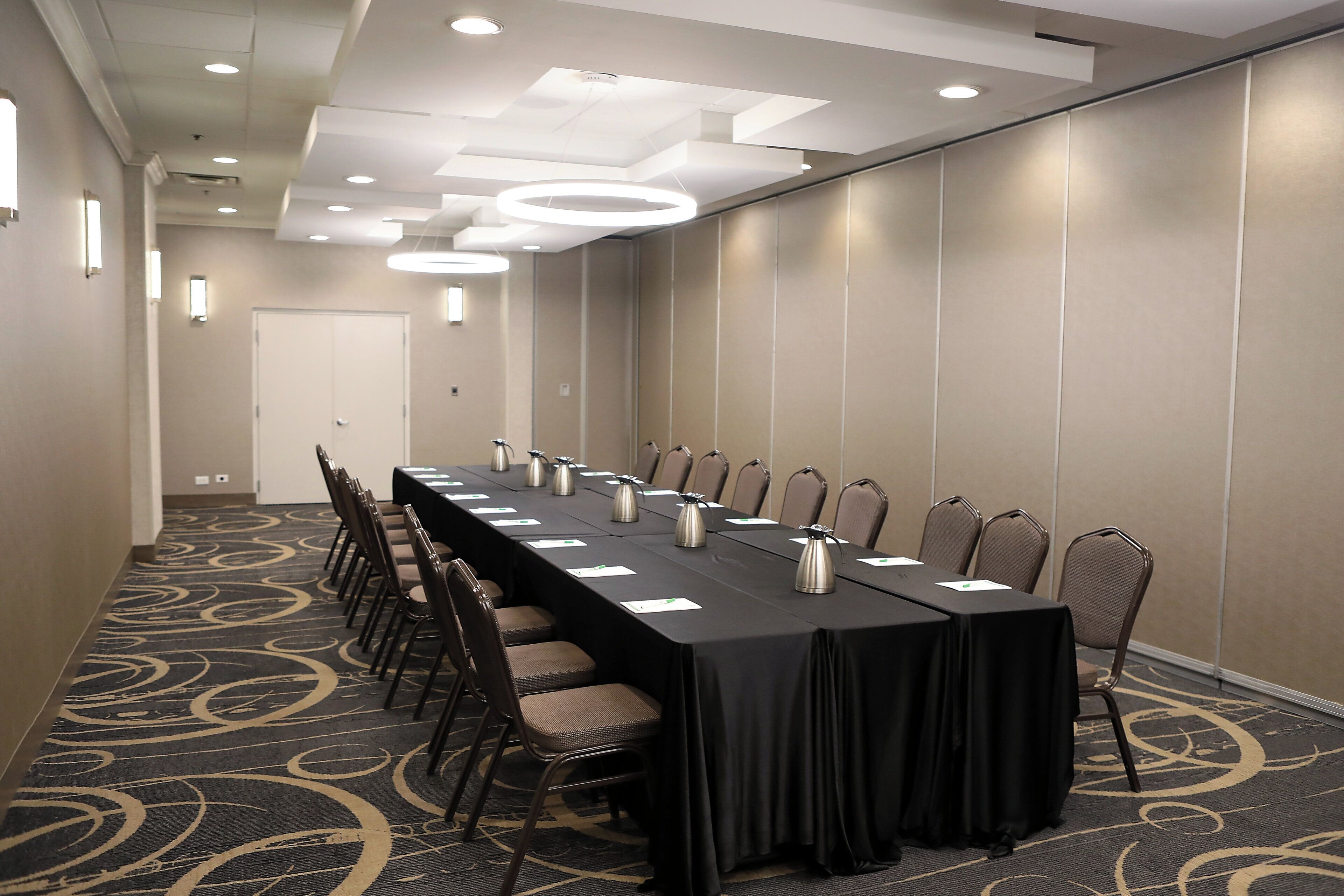 Un salón de conferencias con una larga mesa, sillas y suelo alfombrado.