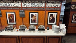A buffet area with various food stations, including a hot foods section, and a breakfast buffet sign indicating a price of $14.95 plus tax.