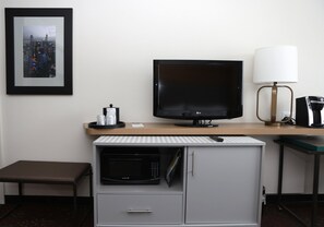 A hotel room with a flat-screen TV, a microwave, a small table with a lamp, and a framed picture on the wall. - Holiday Inn Chicago O'Hare Area by IHG (Chicago)