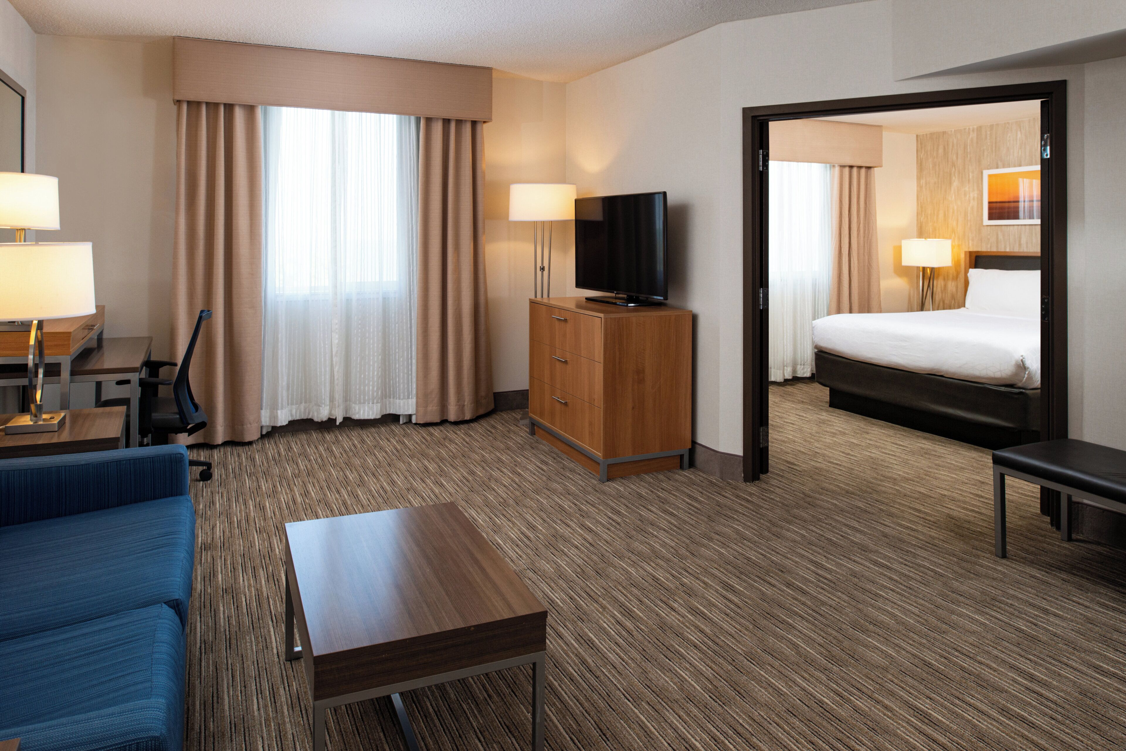 Habitación de hotel con cama, escritorio, televisión y zona de estar.