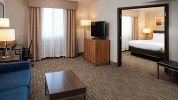 Habitación de hotel con cama, escritorio, televisión y zona de estar.