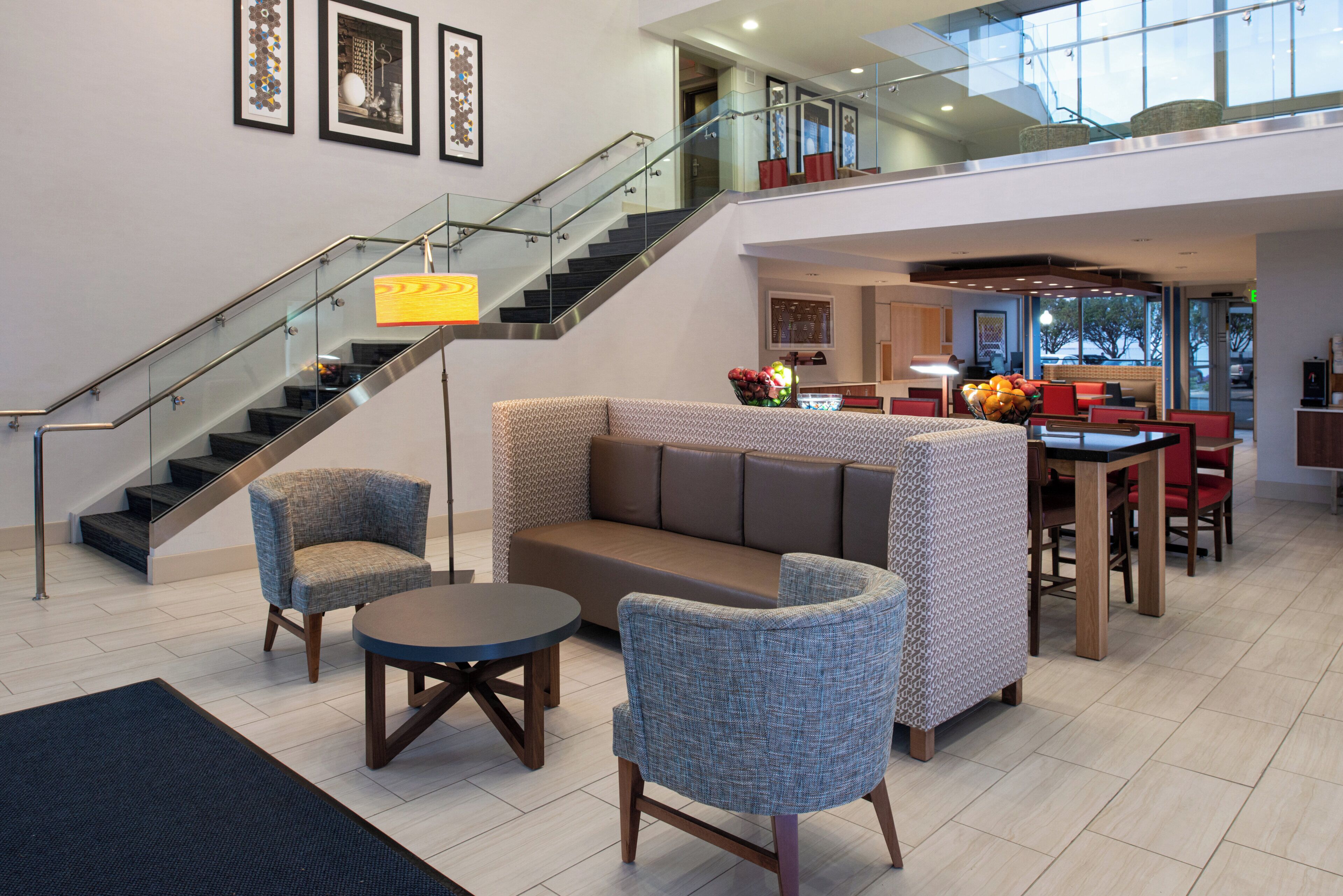 A spacious lobby with a staircase, seating area, and a dining space.