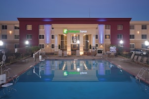 Un hotel Holiday Inn Express con piscina, zona de estar exterior y entrada bien iluminada.