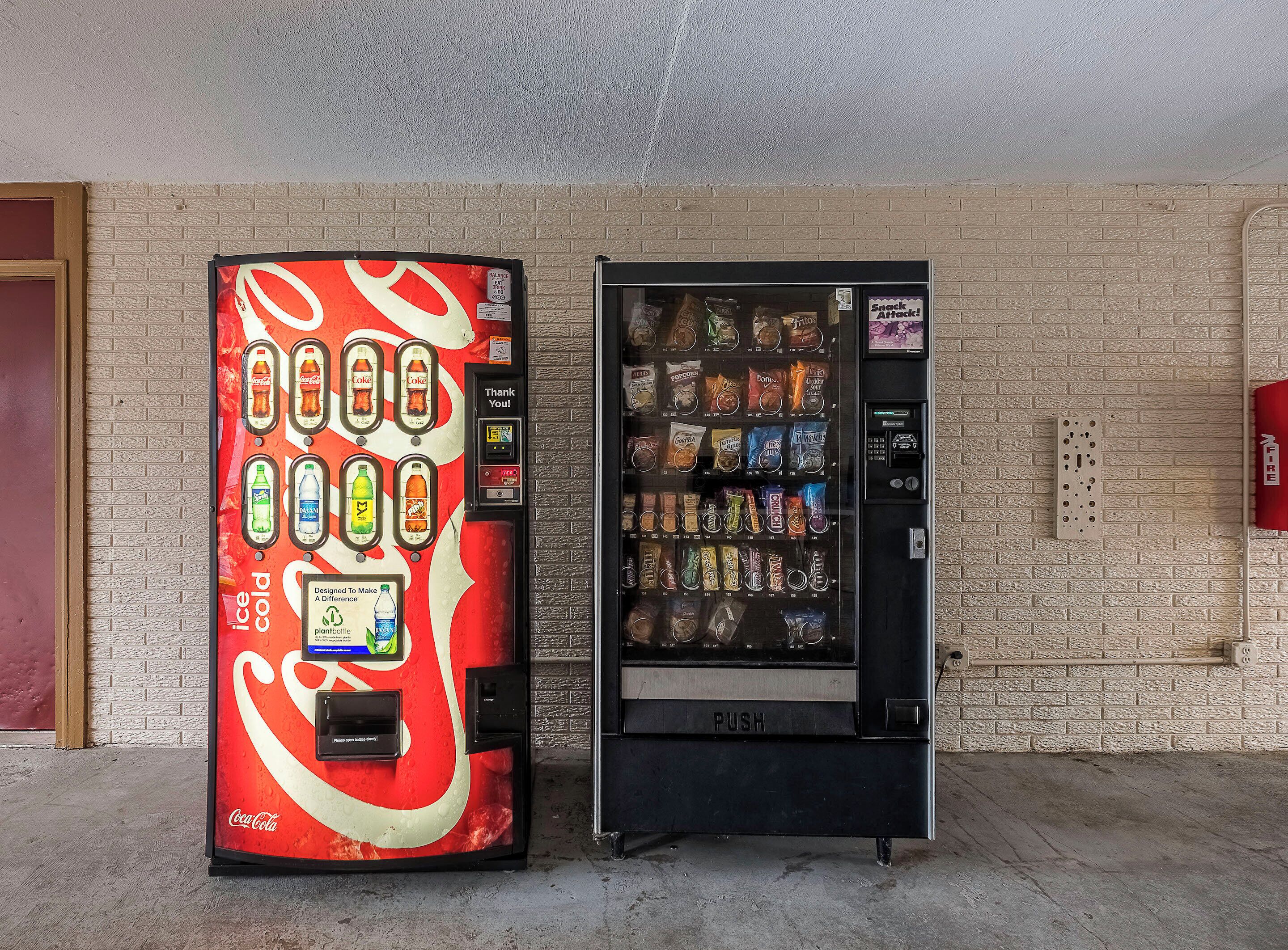 Two vending machines, one with a Coca-Cola design and the other with snacks.