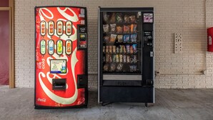 Two vending machines, one with a Coca-Cola design and the other with snacks. - Red Roof Inn Florence - Civic Center (Florence)
