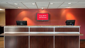 A reception desk with a sign stating "Free Wi-Fi All Rooms" and two monitors. - Red Roof Inn Florence - Civic Center (Florence)