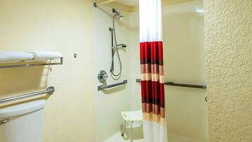 Un baño con inodoro, ducha con cabezal de ducha manual y toallero.