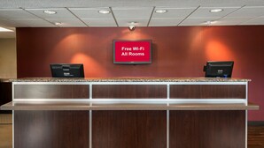 A reception desk with a sign stating "Free Wi-Fi All Rooms" and two monitors. - Red Roof Inn Florence - Civic Center (Florence)