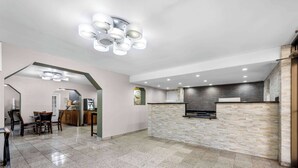 A spacious kitchen with a stone backsplash, a dining area with a table and chairs, and a modern ceiling light fixture. - Days Inn by Wyndham Raleigh Midtown (Raleigh)