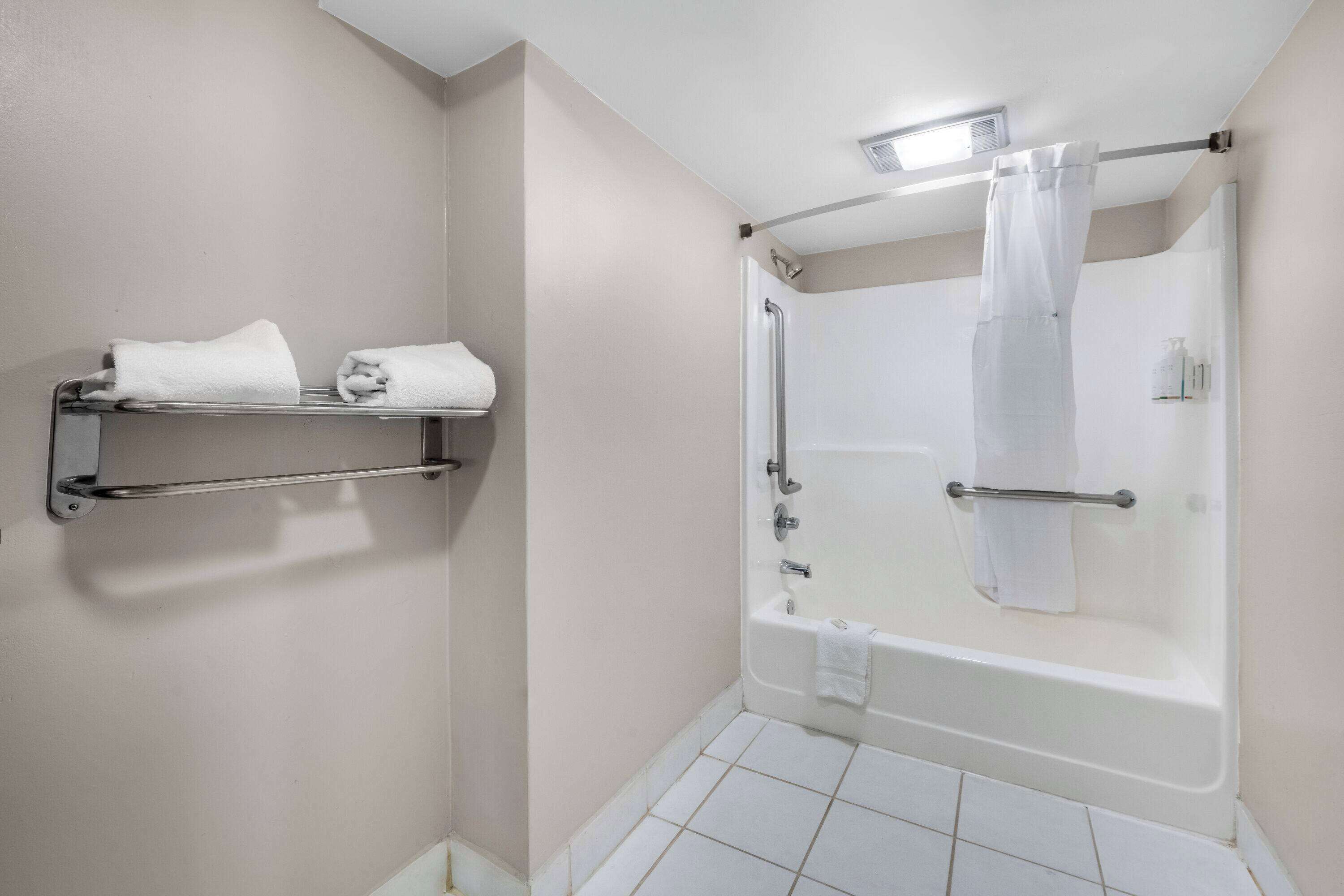 Un bagno con vasca, doccia e porta asciugamani con asciugamani.
