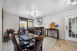 A dining area with a large table and chairs, a small table with condiments, and a door with a glass panel.