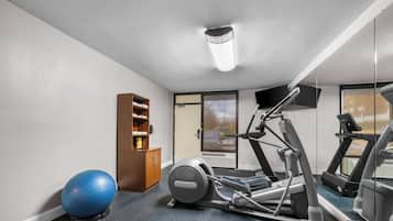 A gym with exercise equipment, a blue exercise ball, and a wooden cabinet.
