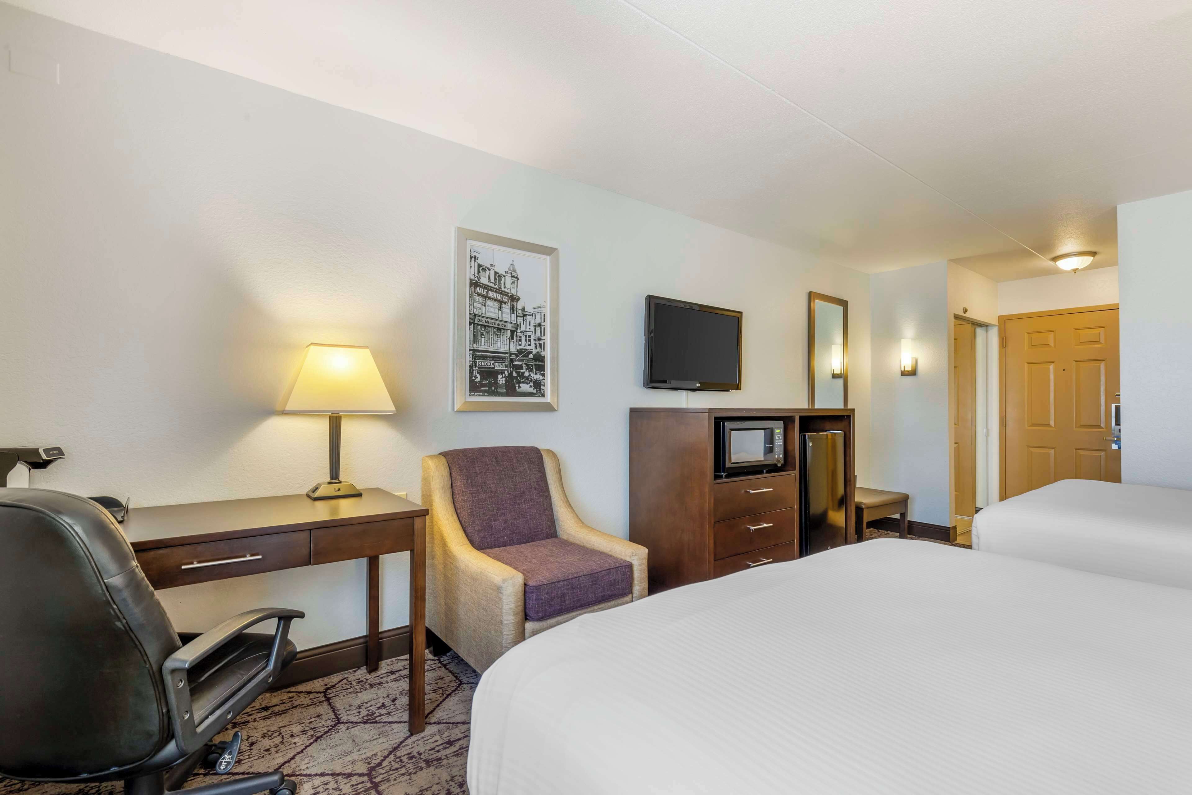 Een hotelkamer met een bed, bureau, stoel, televisie en een magnetron.