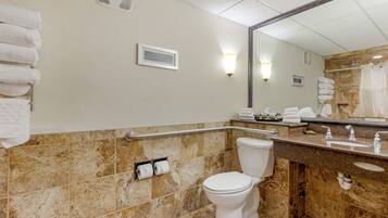 A bathroom with a toilet, sink, and mirror. There are towels stacked on the wall and a shower curtain.
