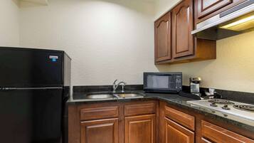 A compact kitchen with a refrigerator, microwave, sink, and stove.