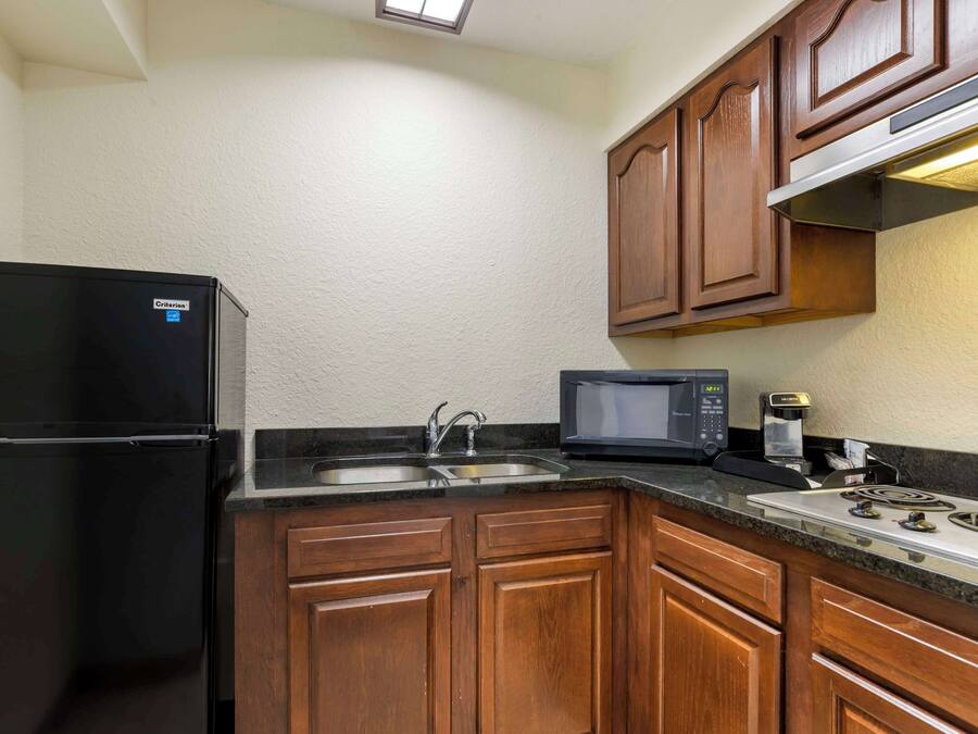 A compact kitchen with a refrigerator, microwave, sink, and stove.