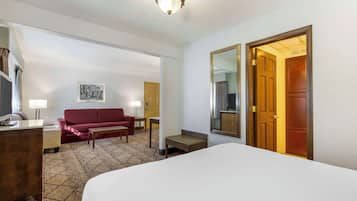 Una habitación de hotel con una cama, un sofá rojo, un escritorio, una lámpara y un espejo.
