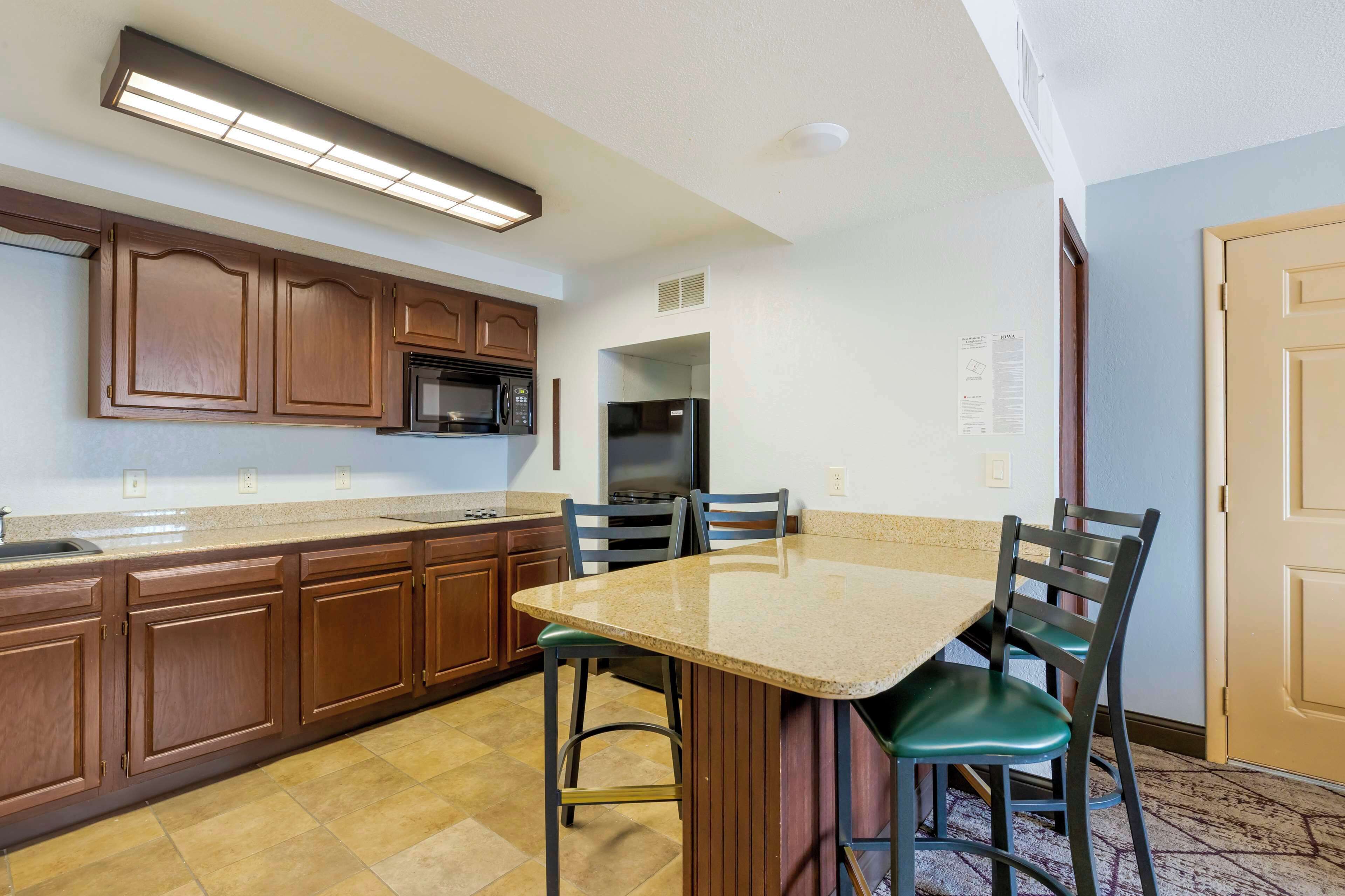 A kitchen with wooden cabinets, a granite countertop, and a dining table with chairs.