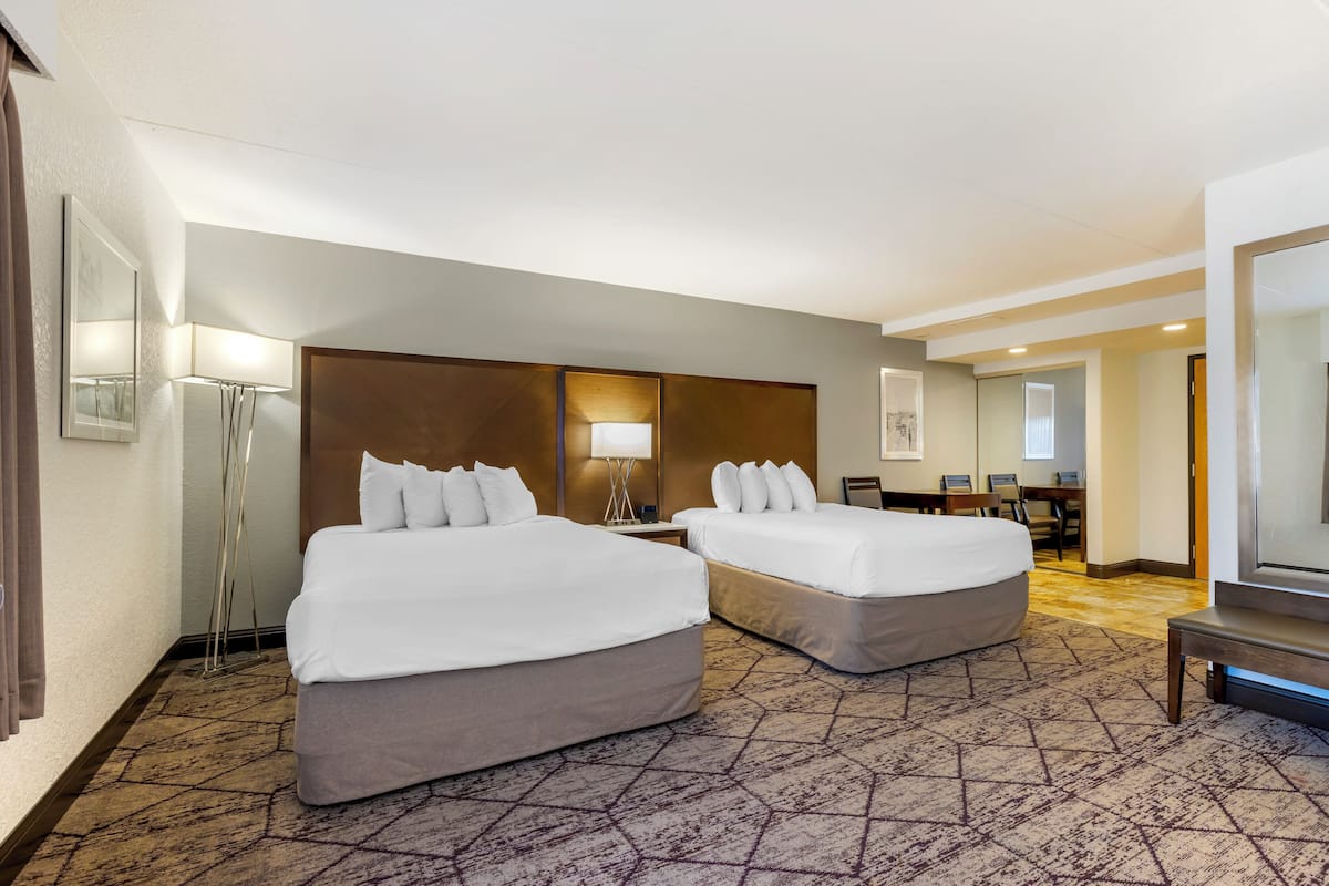 A hotel room with two beds, a desk, and a chair.