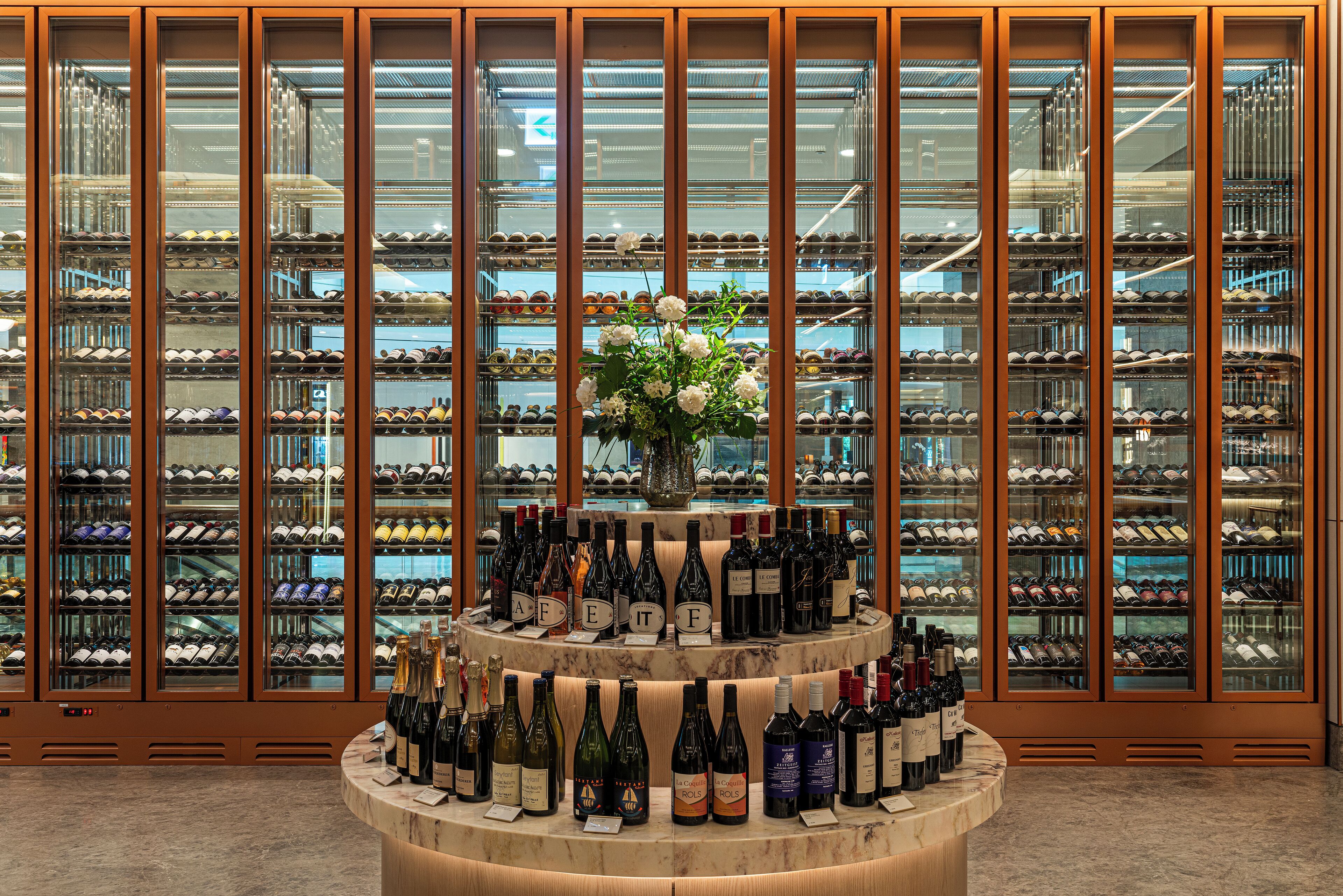 A wine cellar with a central display of wine bottles and a floral arrangement.