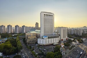 Un hotel alto con un letrero llamativo, rodeado de otros edificios y una calle concurrida.