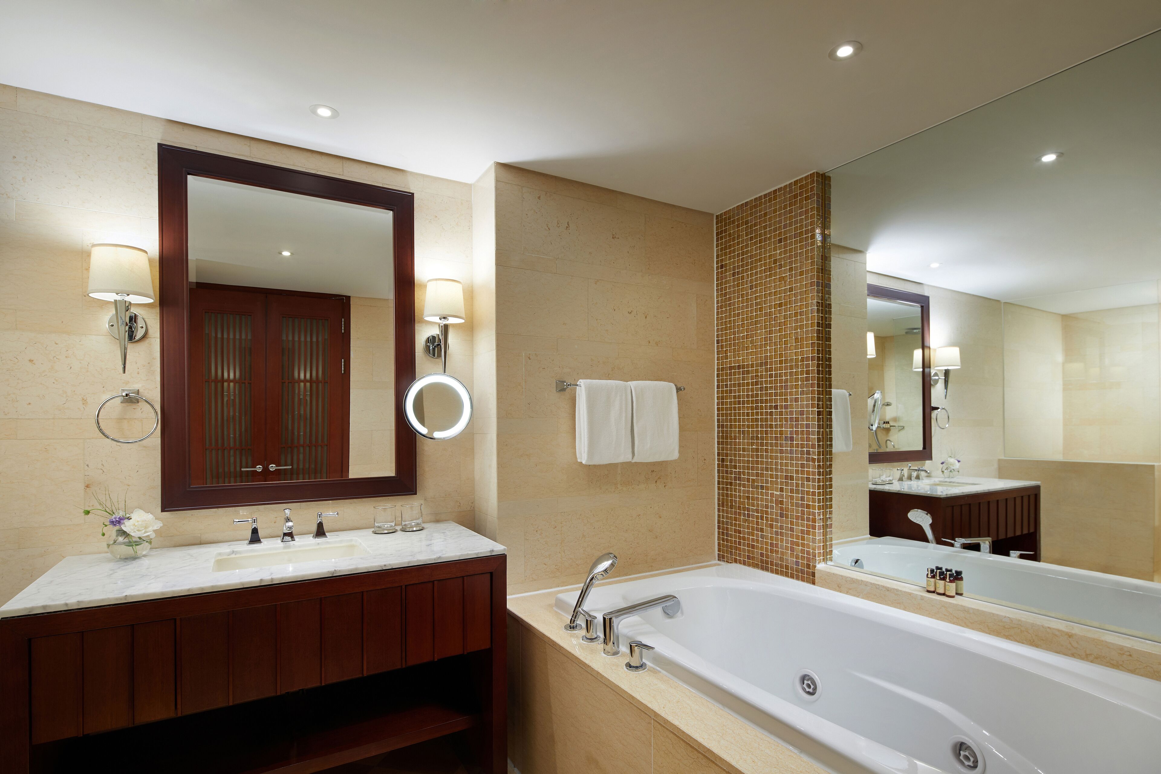 Un baño moderno con un espejo grande, dos lavamanos, una bañera y un perchero para toallas.