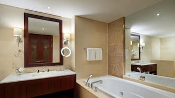 Un baño moderno con un espejo grande, dos lavamanos, una bañera y un perchero para toallas.