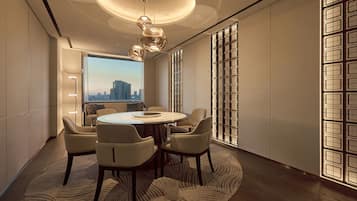 Un comedor moderno con una mesa redonda, sillas y vistas a la ciudad a través de amplios ventanales.