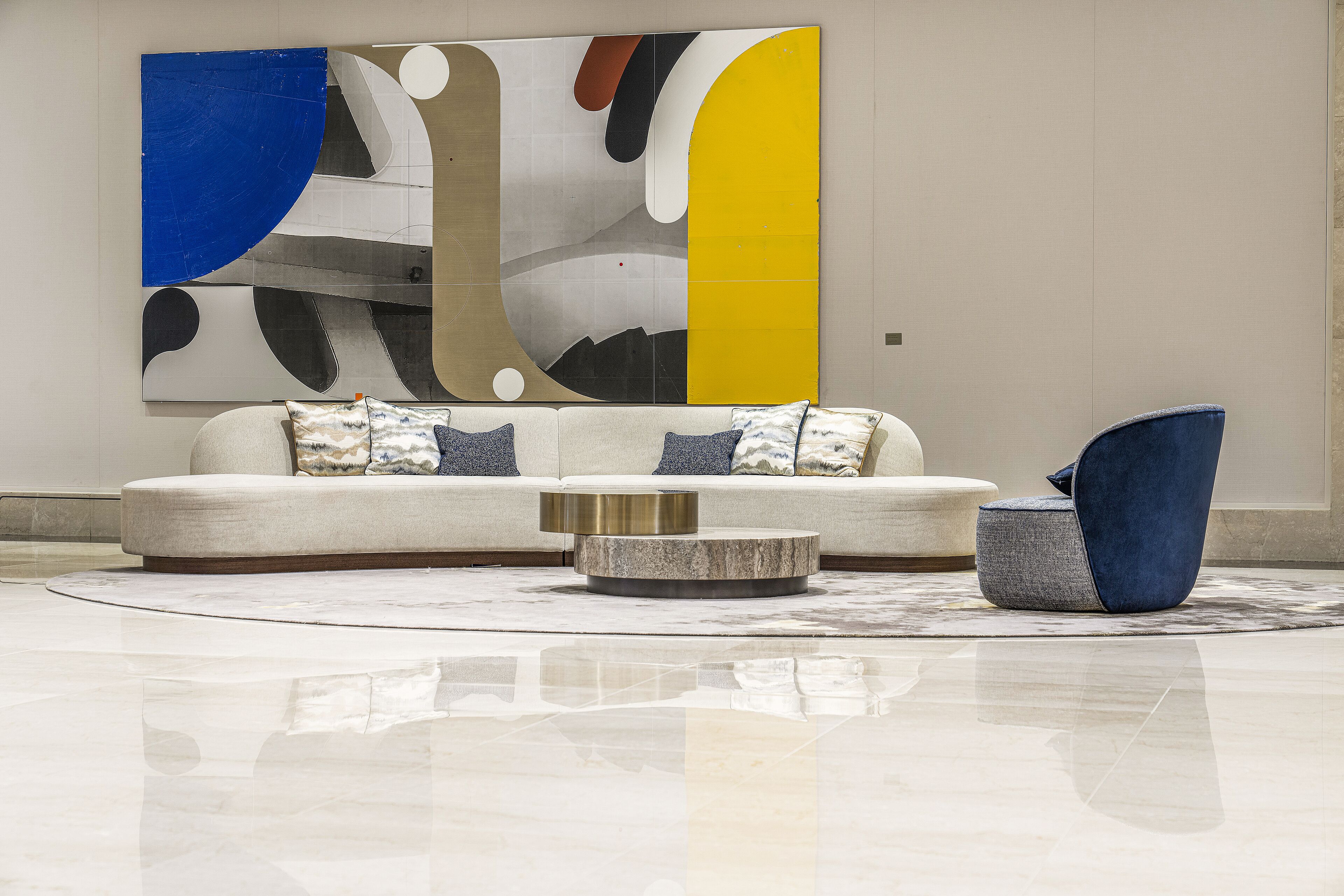 A modern living room with a sectional sofa, a round coffee table, and a blue accent chair.