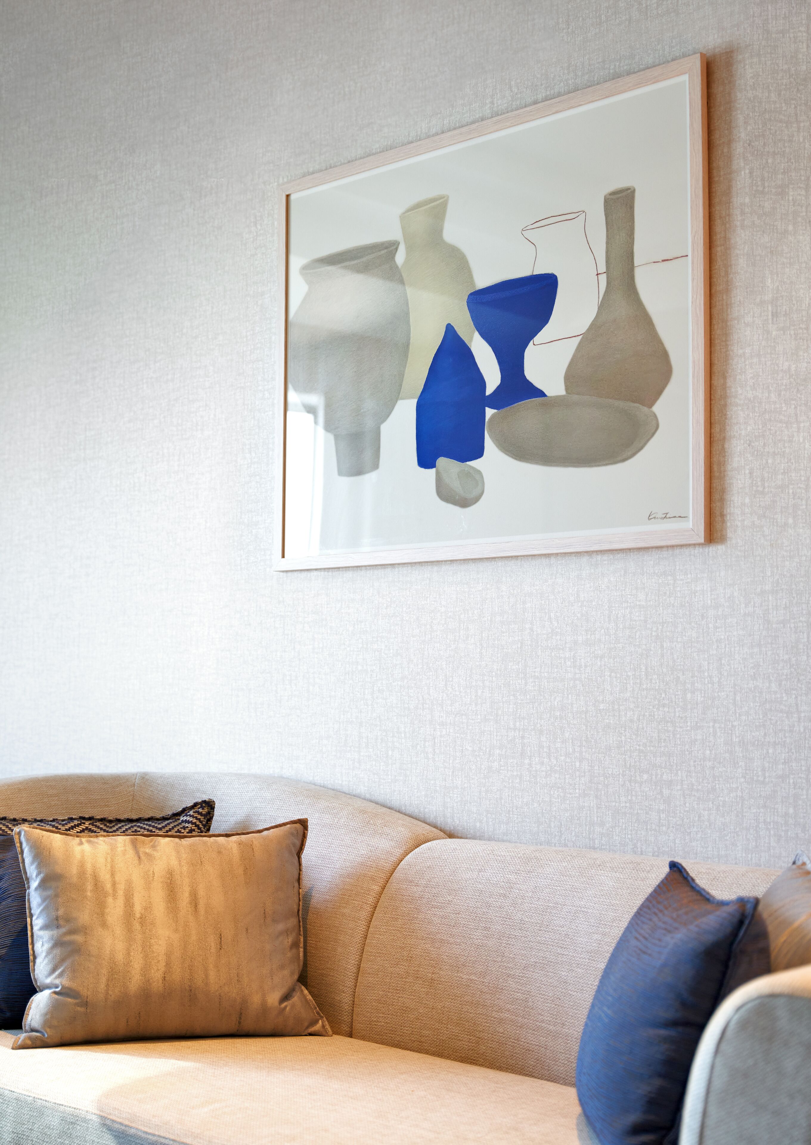 A framed abstract art piece on a wall above a sofa with patterned cushions.