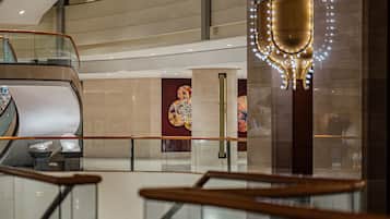 A multi-level interior with glass railings, a central decorative column, and a view of a lower floor.