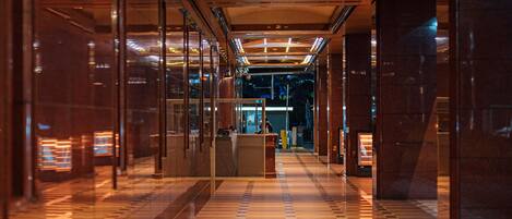 A corridor with reflective flooring and glass doors, leading to a reception area.