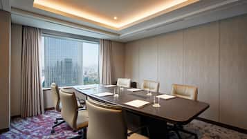 Un salón de conferencias con una gran mesa, seis sillas y vistas a la ciudad a través de amplias ventanas.