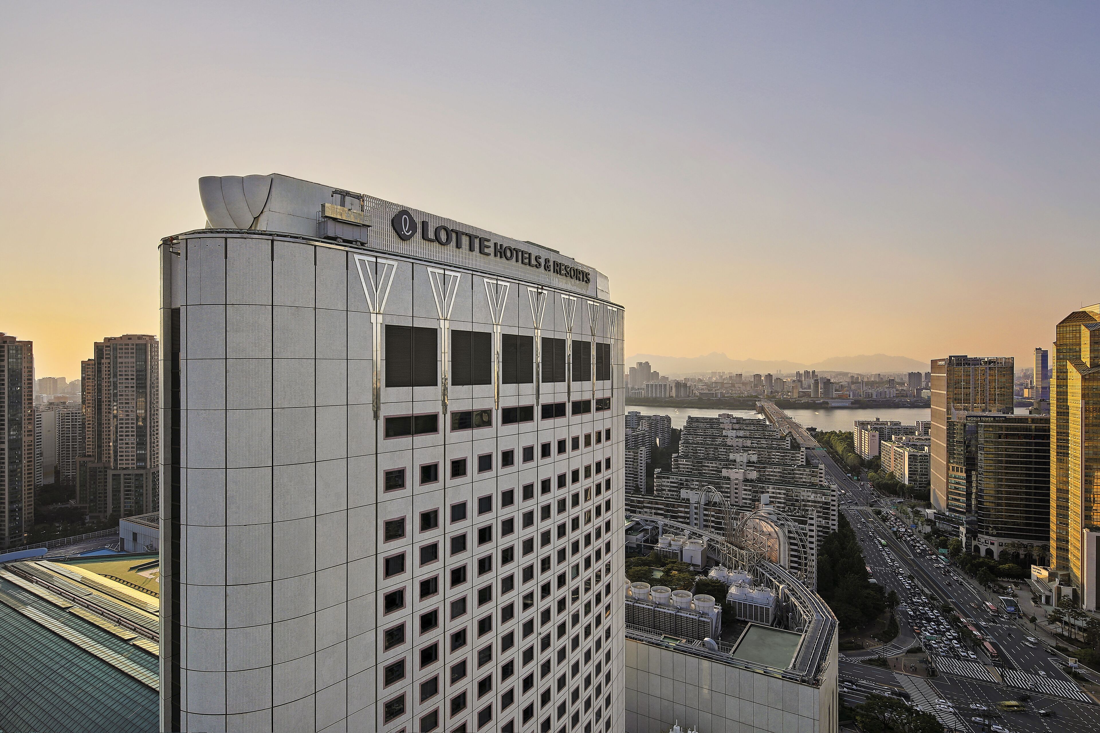 Ett högt hotell med modern design, som har en tydlig skylt med Lotte Hotels & Resorts logotyp.