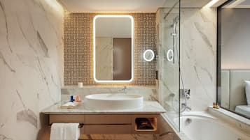 Un baño moderno con lavamanos de mármol, un espejo grande y una ducha con cerramiento de vidrio.