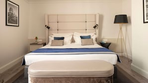 A neatly arranged bedroom with a large bed, bedside tables, a floor lamp, and framed pictures on the walls. - Cerretani Hotel Firenze - MGallery Collection (Florence)