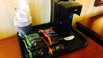 A tray with a coffee maker, disposable cups, and coffee pods.