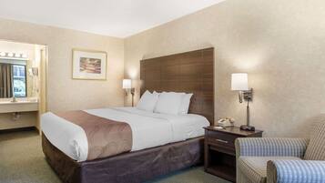 A hotel room with a large bed, bedside lamps, a chair, and a desk with a phone.