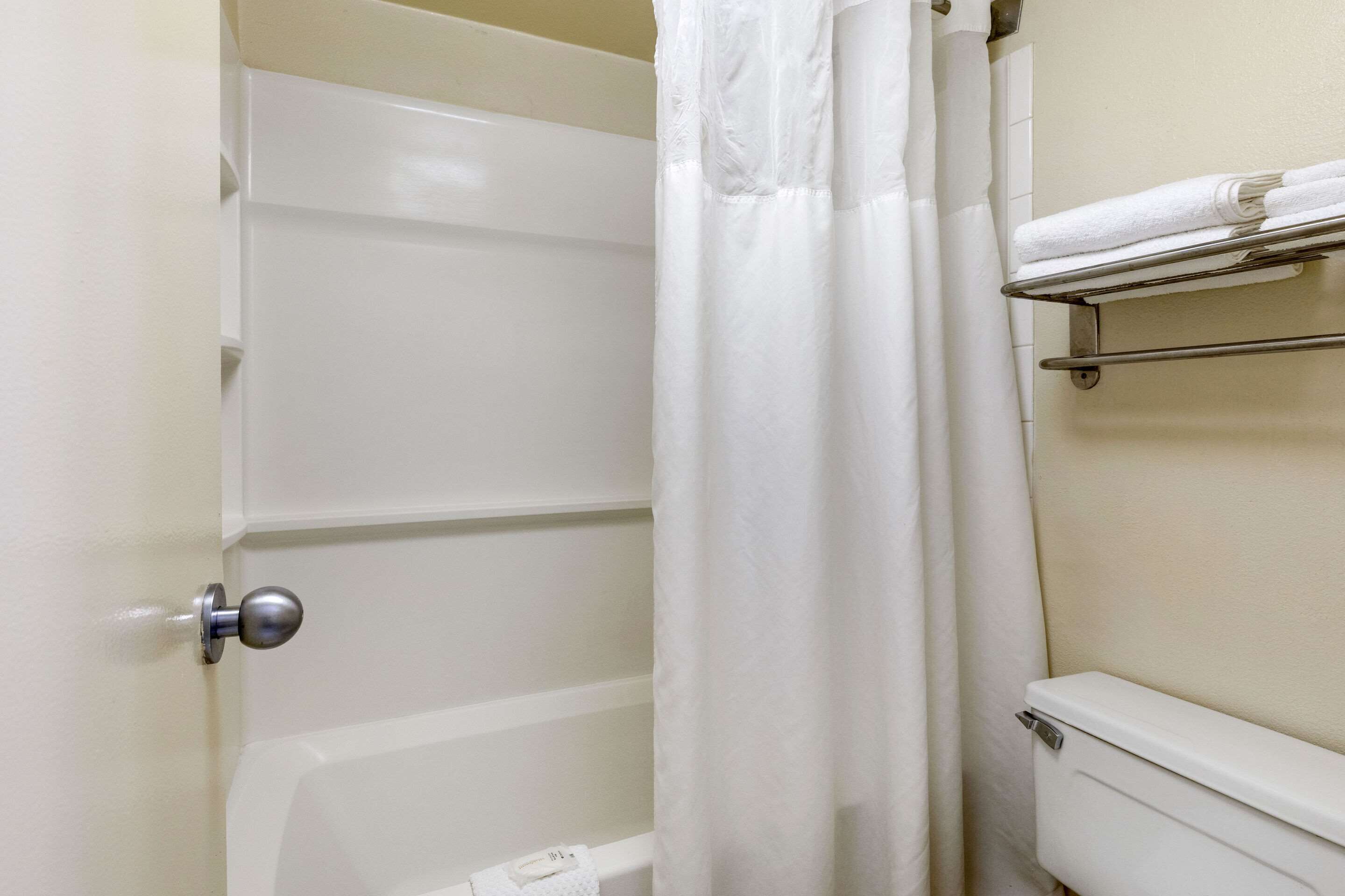 A bathroom with a bathtub, a toilet, a shower curtain, and a towel rack.