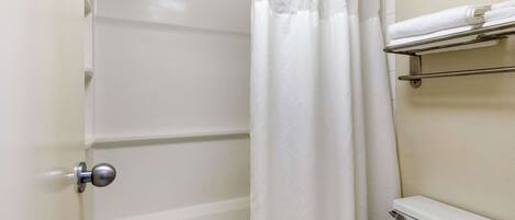 A bathroom with a bathtub, a toilet, a shower curtain, and a towel rack.