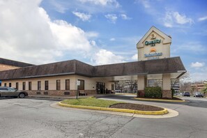 A Quality Inn Suburban Studios building with a clear sky and parked cars.