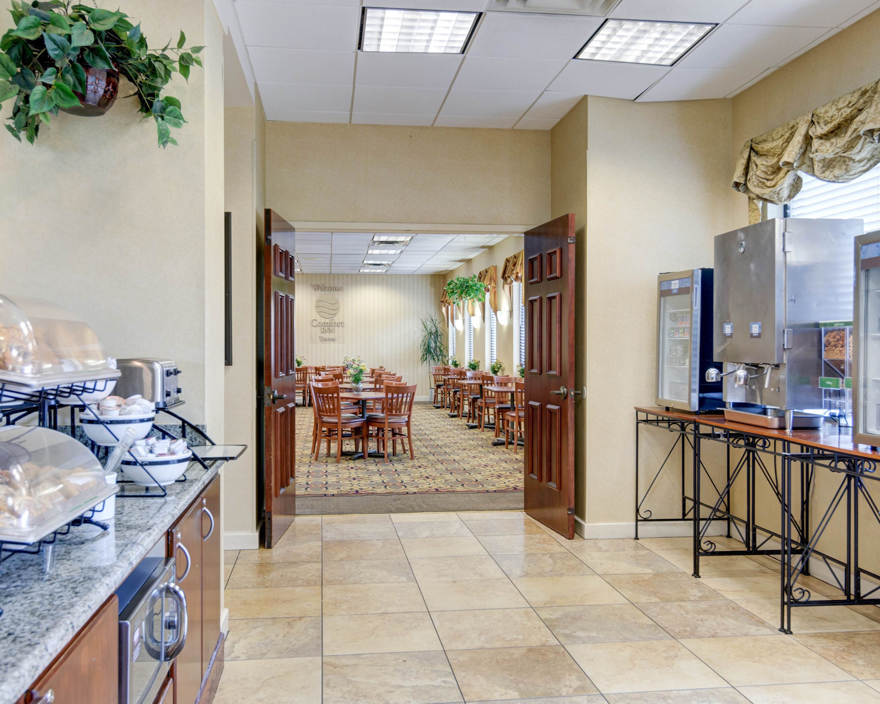 A hotel lobby with a reception desk, a buffet area, and a dining area with tables and chairs.