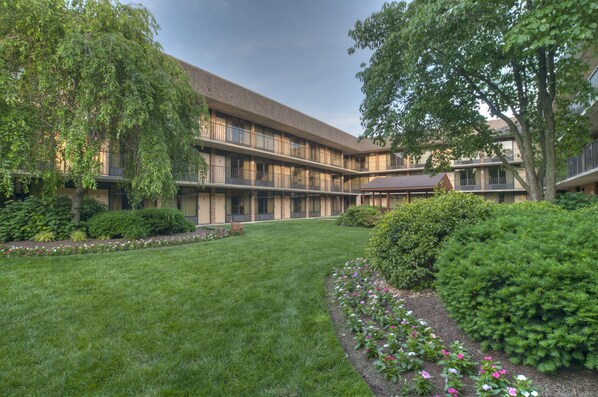 A courtyard with a building featuring multiple balconies and a well-maintained lawn.