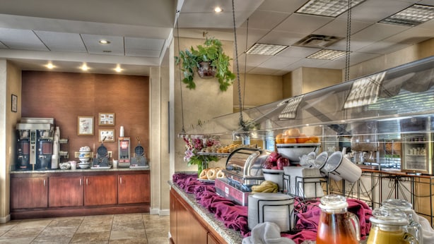 Zona de buffet con una variedad de alimentos, una estación de café y una planta colgante.