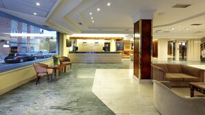 A hotel lobby with a reception desk, seating area, and a view of the street. - Exe Salamanca (Salamanca)
