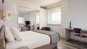 A hotel room with a large bed, a desk, a chair, and a television. - Exe Salamanca (Salamanca)