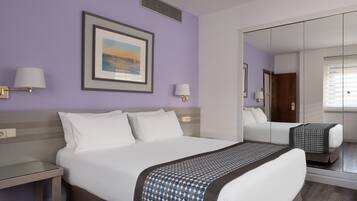 Habitación de hotel con una cama grande, dos mesitas de noche, un espejo y un cuadro en la pared.