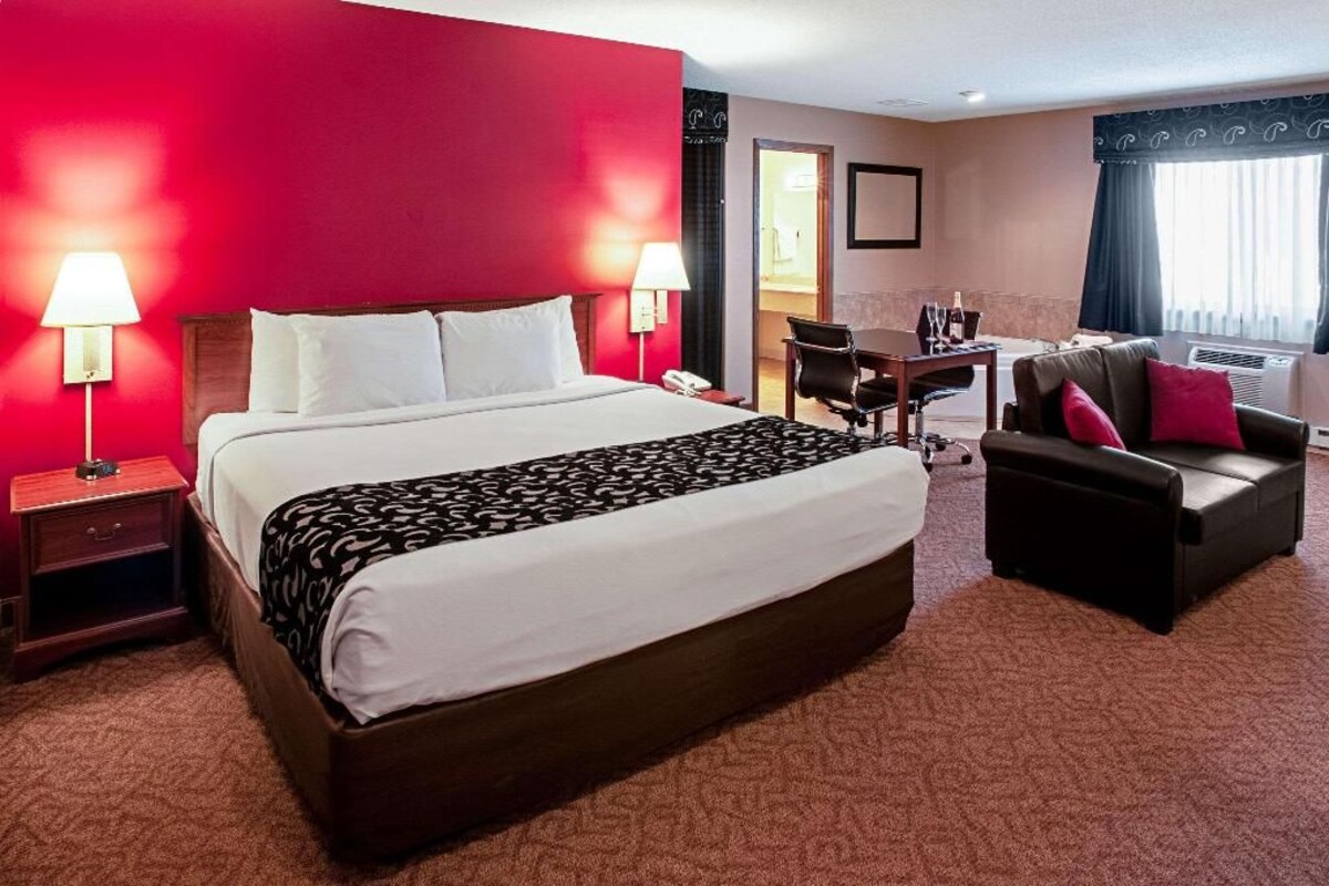 A hotel room with a large bed, a desk, a chair, and a sofa.
