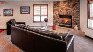 A lobby with a stone fireplace, leather sofa, and framed artwork on the walls.